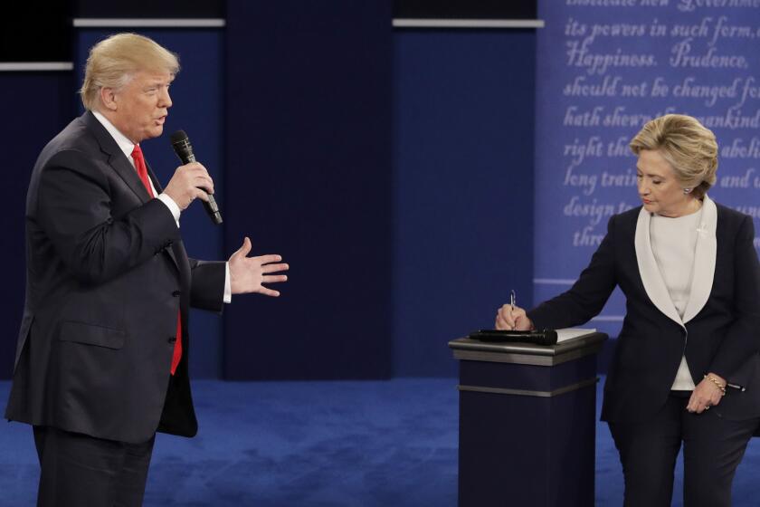 Republican presidential nominee Donald Trump speaks while Democratic presidential nominee Hillary Clinton takes notes.