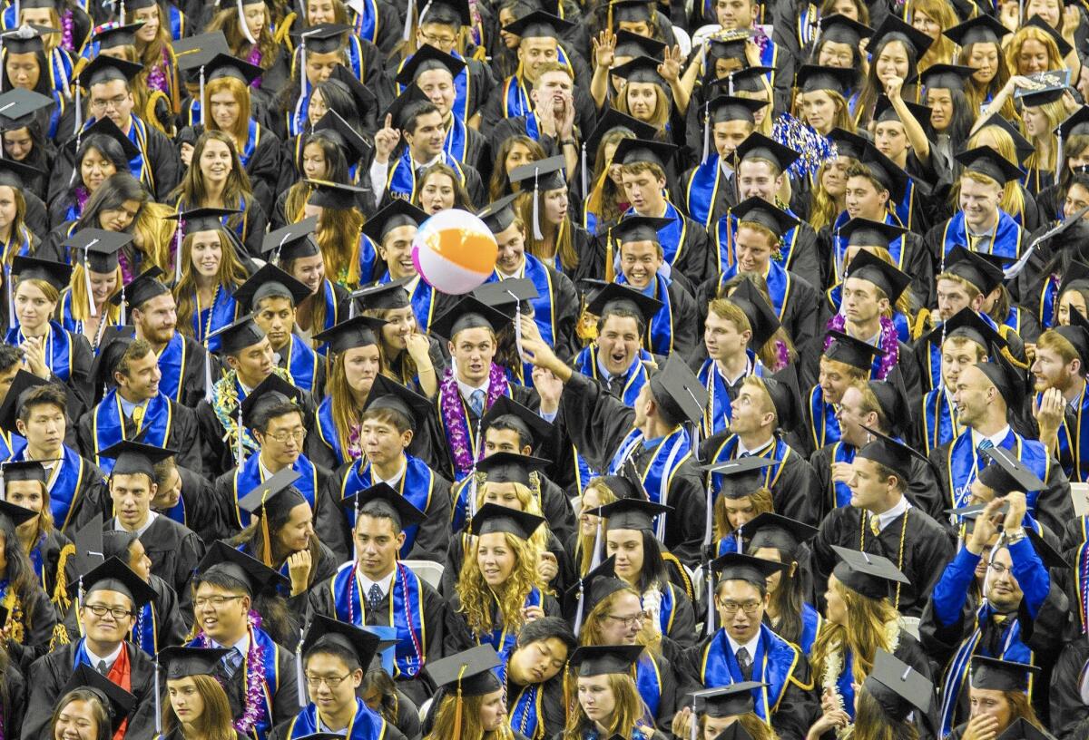 Graduating seniors toss a beach ball during commencement at UCLA. A new report found that students who iidentify as being from Chinese, Japanese, Indian, Vietnamese or Korean families tend to have significantly higher graduation rates at the UC and Cal State systems than do native Hawaiians, other Pacific Islanders and students from Laos.