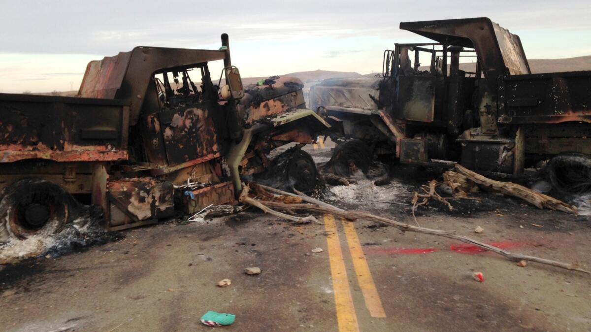 The burned-out husks of heavy trucks sit on Highway 1806 near Cannon Ball, N.D.