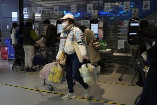 A resident carries her groceries near cashier machines at a supermarket in Beijing, Friday, Nov. 25, 2022. Residents of China's capital were emptying supermarket shelves and overwhelming delivery apps Friday as the city government ordered accelerated construction of COVID-19 quarantine centers and field hospitals. (AP Photo/Ng Han Guan)