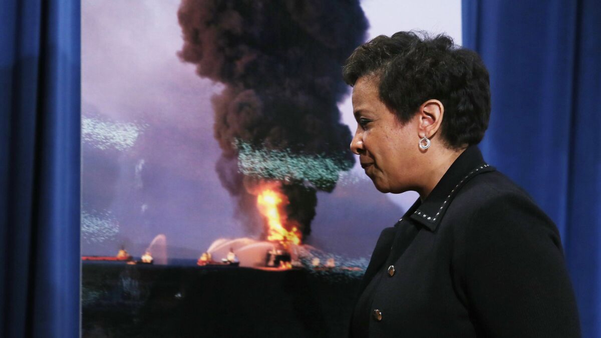 Atty. Gen. Loretta Lynch walks past a photo of the 2010 Deepwater Horizon platform in flames after she announced the resolution of claims against BP.