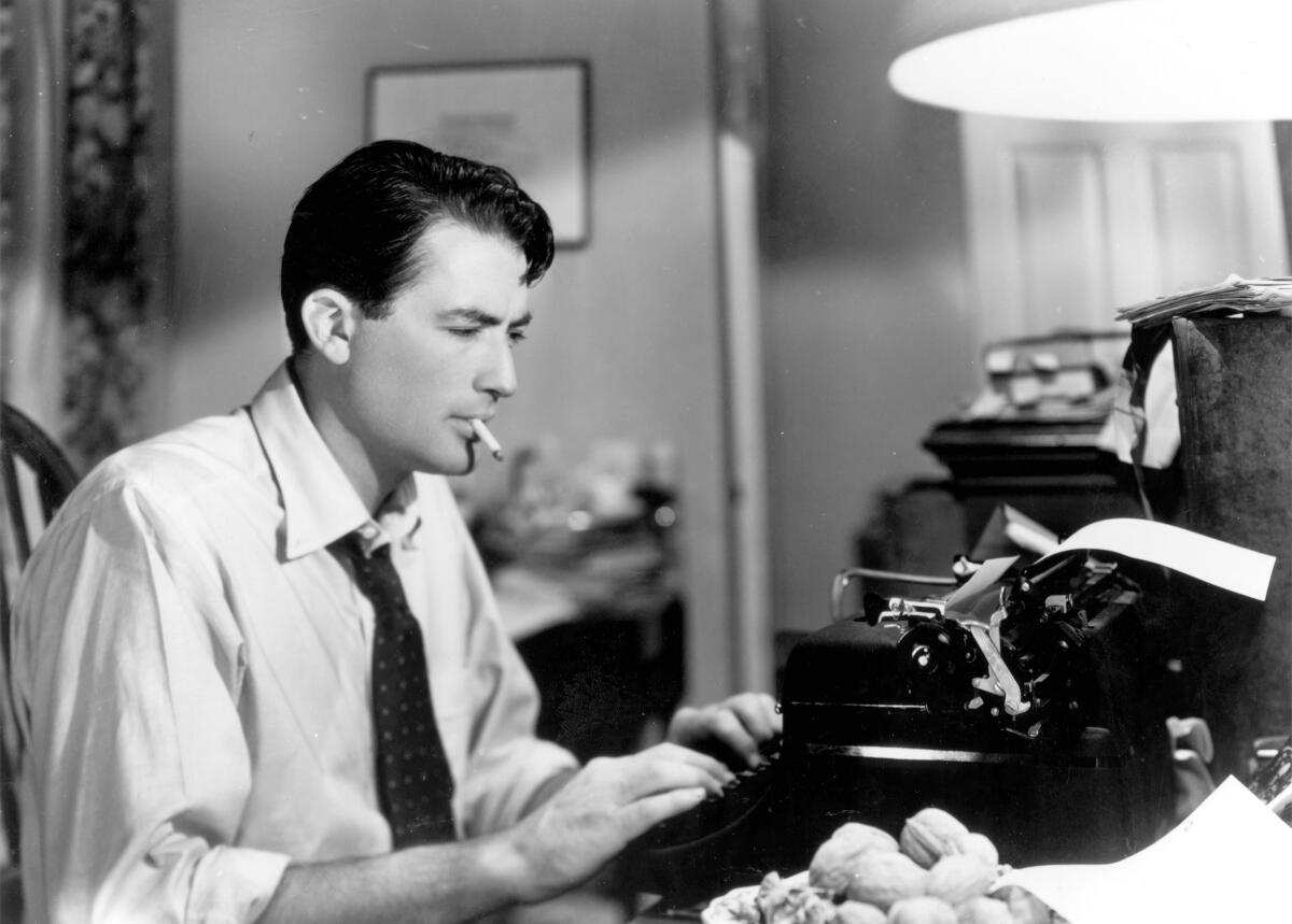 black and white photo of a man smoking and typing at a typewriter 