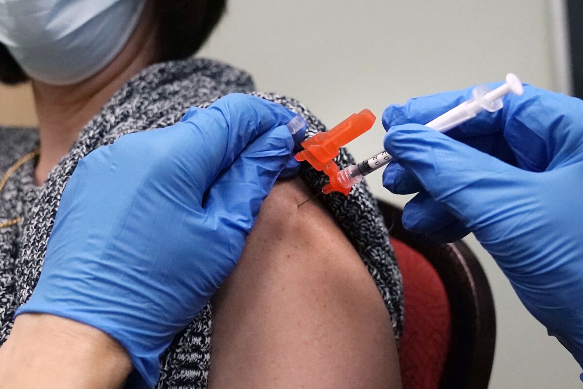 FILE - A woman receives a COVID-19 vaccine injection by a pharmacist at a clinic in Lawrence, Mass., on Wednesday, Dec. 29, 2021. On Friday, March 11, 2022, The Associated Press reported on stories circulating online incorrectly claiming people who have received COVID-19 vaccine booster shots are at a greater risk of dying from the virus. (AP Photo/Charles Krupa, File)
