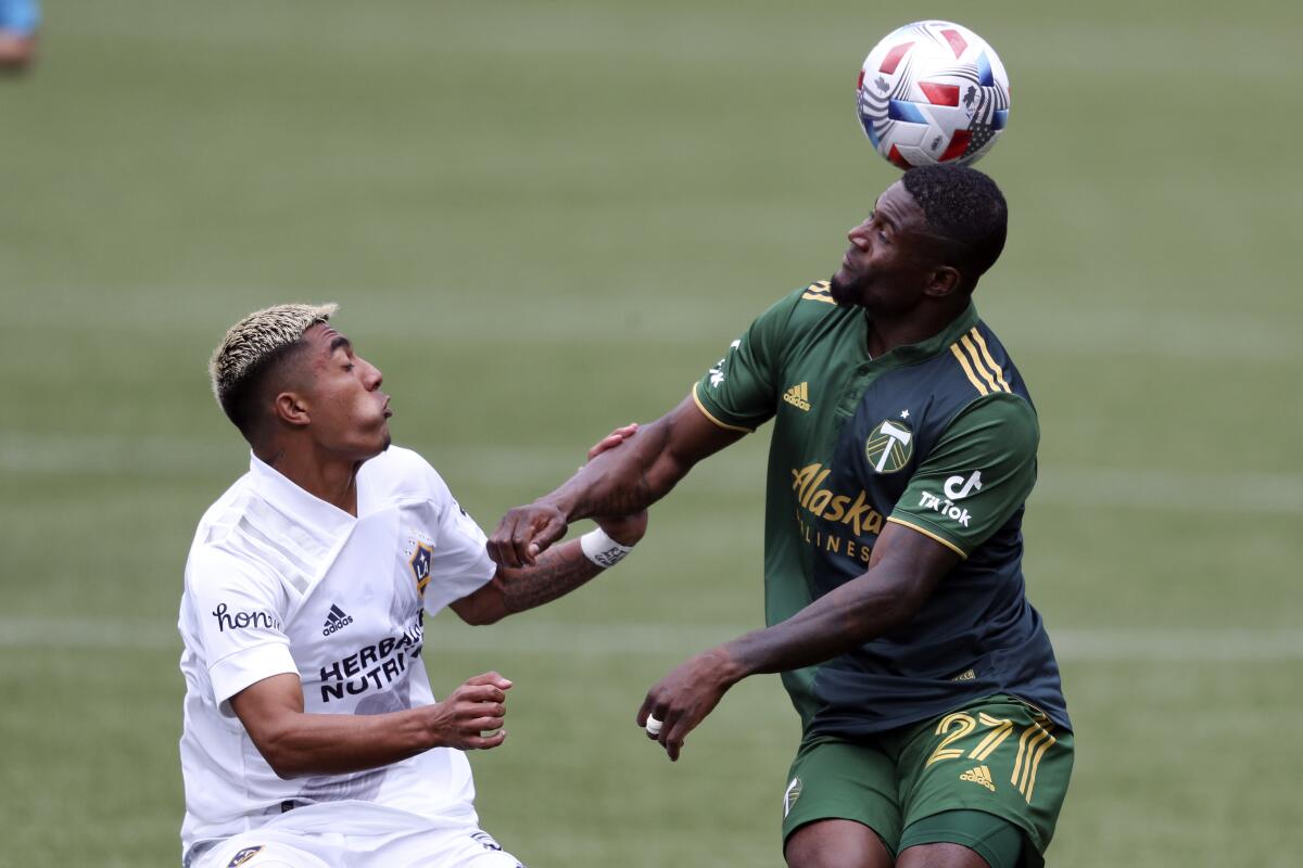 Portland Timbers midfielder Dairon Asprilla heads the ball in front of Galaxy defender Julian Araujo.