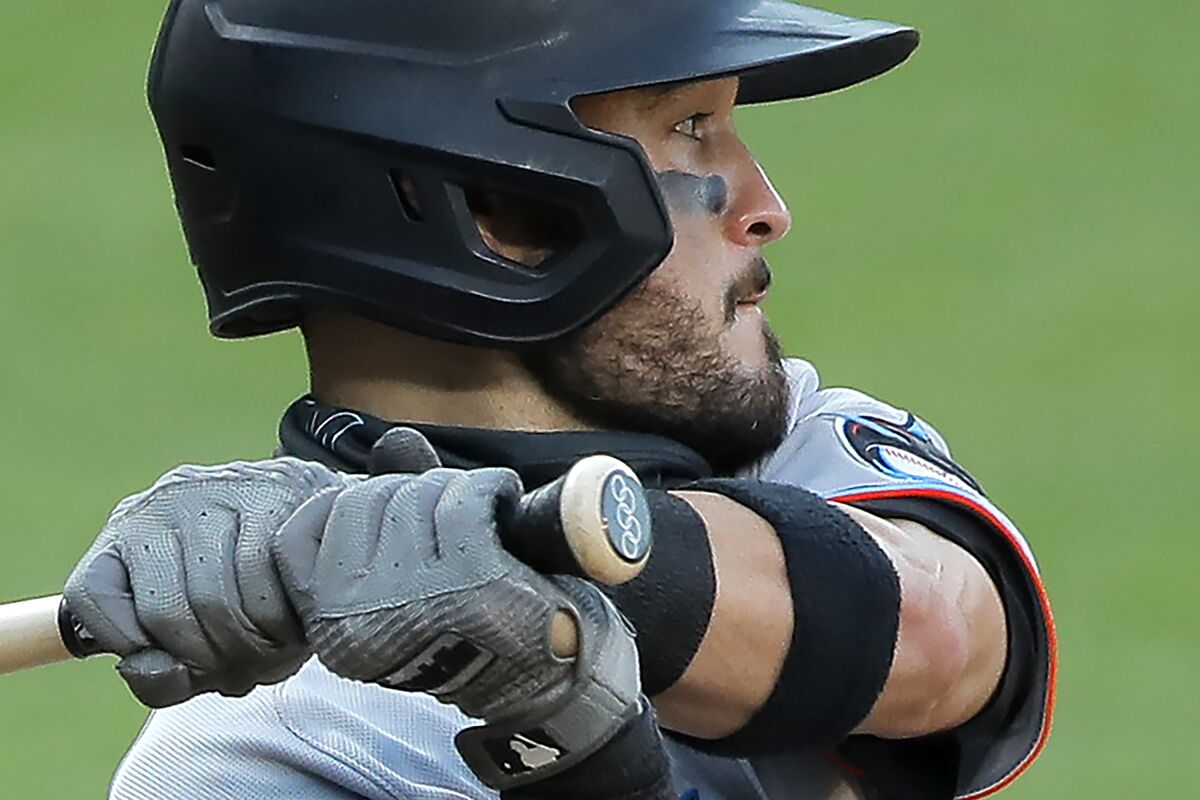 FILE - The Olympic rings are seen on the knob of Miami Marlins' Eddy Alvarez's bat as he swings at a pitch from the Baltimore Orioles during the seventh inning in the first game of a baseball doubleheader in Baltimore, in this Wednesday, Aug. 5, 2020, file photo. Alvarez, having won a silver in speed skating at Sochi in 2014, helped the U.S. reach the Olympic baseball tournament and could become only the third American to win medals at the summer and winter Games. (AP Photo/Julio Cortez, File)