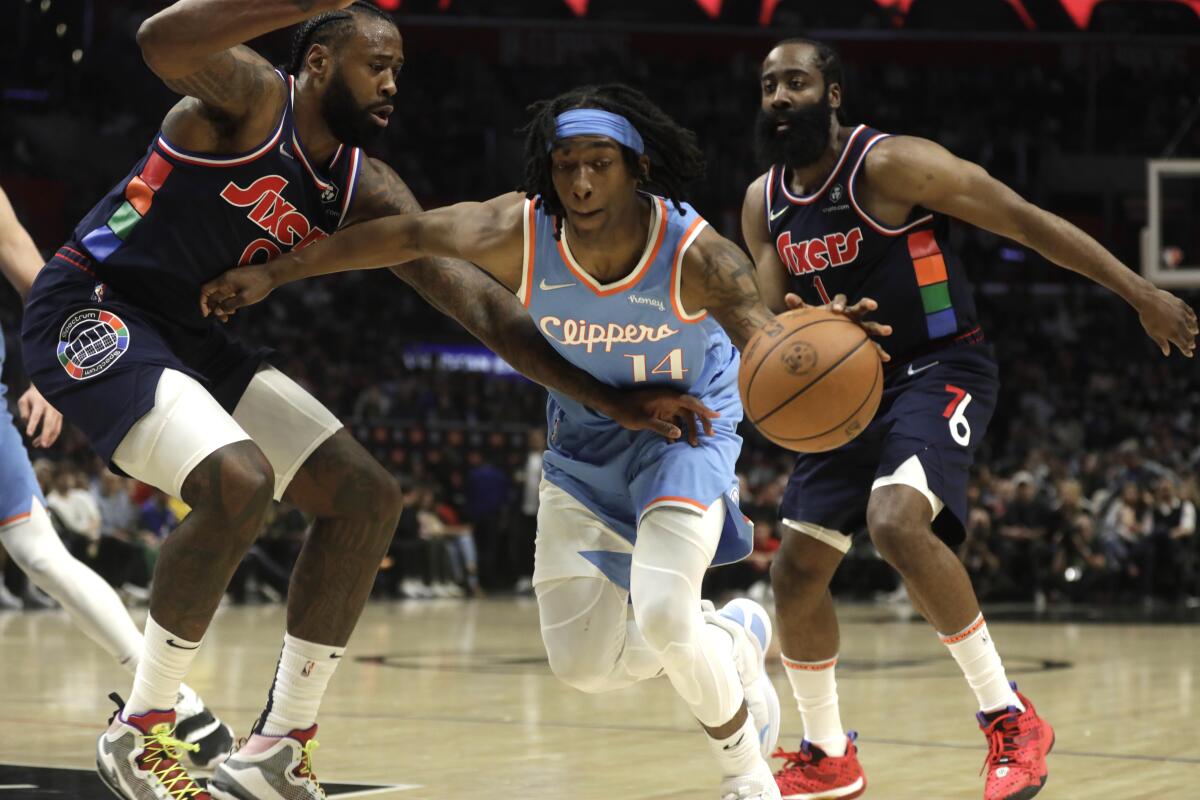 Clippers guard Terance Mann drives between Philadelphia 76ers forward DeAndre Jordan and guard James Harden.