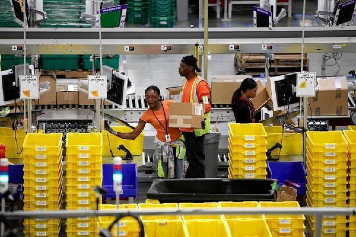 Members of Amazon.com's Prime program have free two-day shipping and, under the new deal with the U.S. Postal Service, can order items Friday and receive them Sunday. Customers outside of Prime will pay the standard shipping costs associated with business day delivery. Above, workers at Amazon's fulfillment center in San Bernardino.