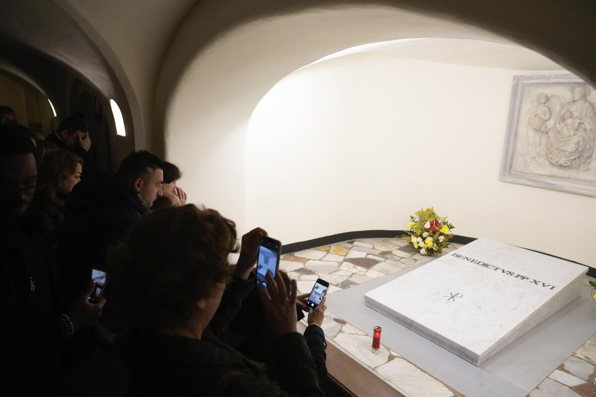 People visit the tomb of Pope Benedict XVI in the grottoes of St. Peter's Basilica at the Vatican.