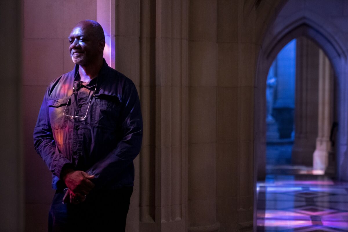 Artist Kerry James Marshall stands in stained glass beams.