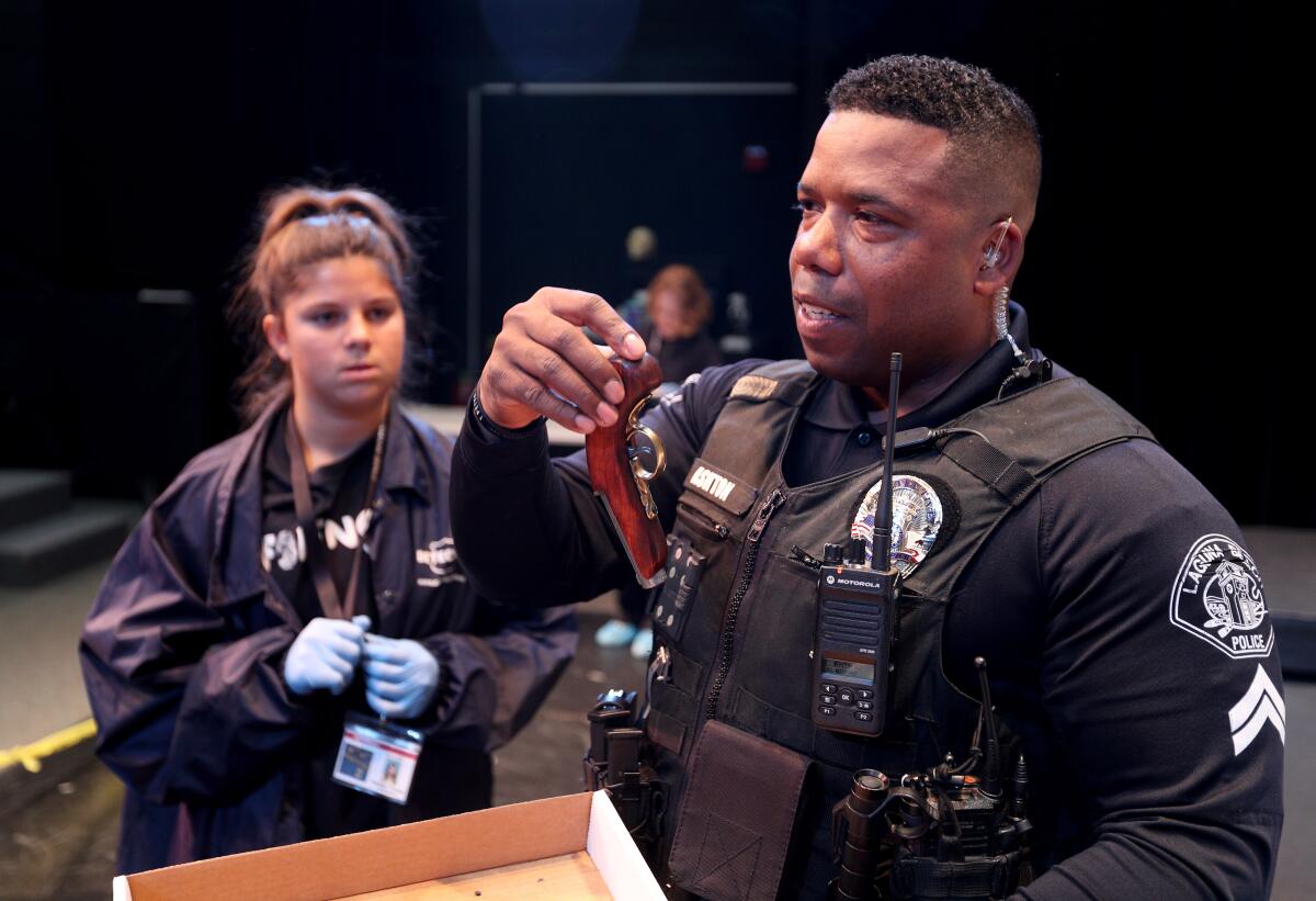 School resource officer Cpl. Cornelius Ashton shows a replica gun found by forensics students while conducting a mock crime scene investigation based on the assassination of former President Abraham Lincoln at Thurston Middle School in Laguna Beach on Thursday. Laguna Beach police officers helped students investigate.