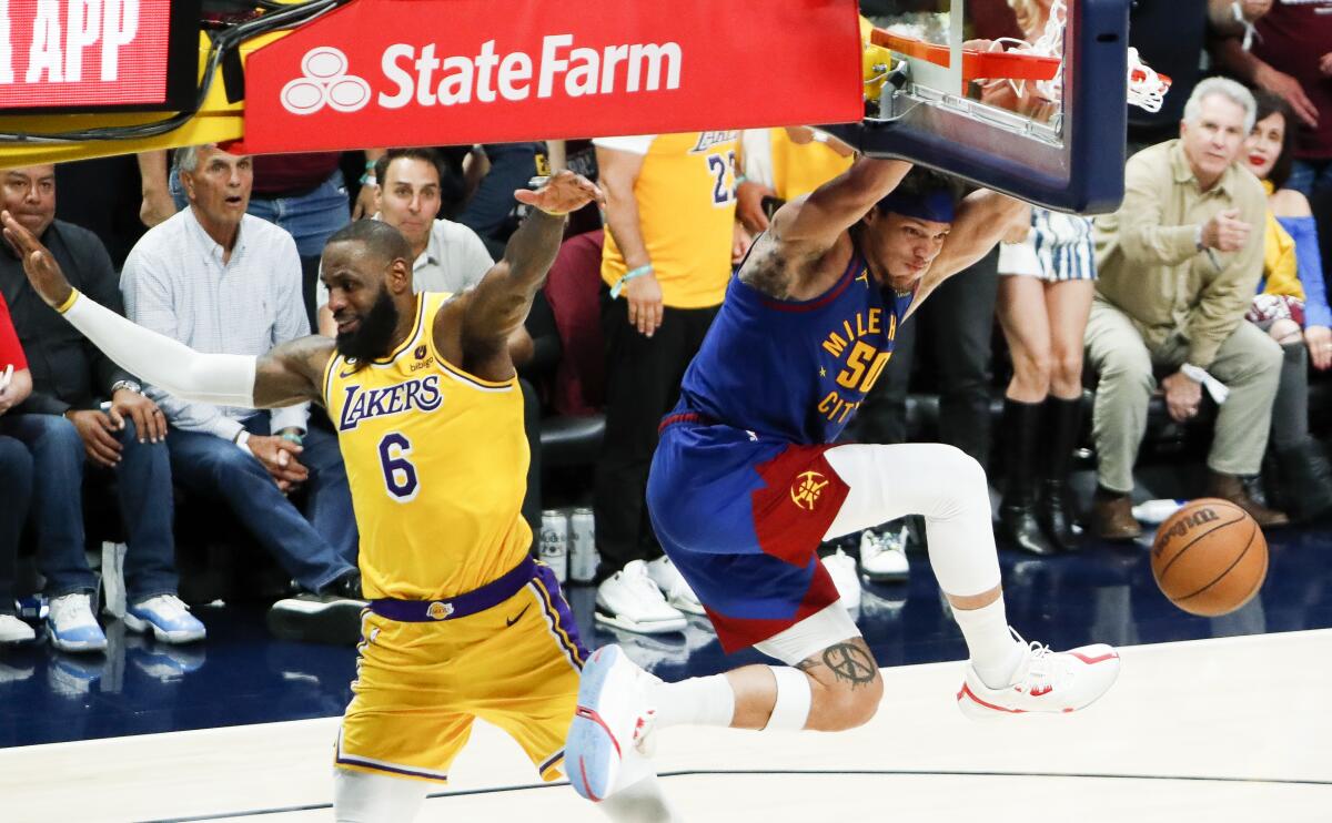 Nuggets forward Aaron Gordon, right, hangs on the rim after dunking on a fast break against Lakers forward LeBron James.
