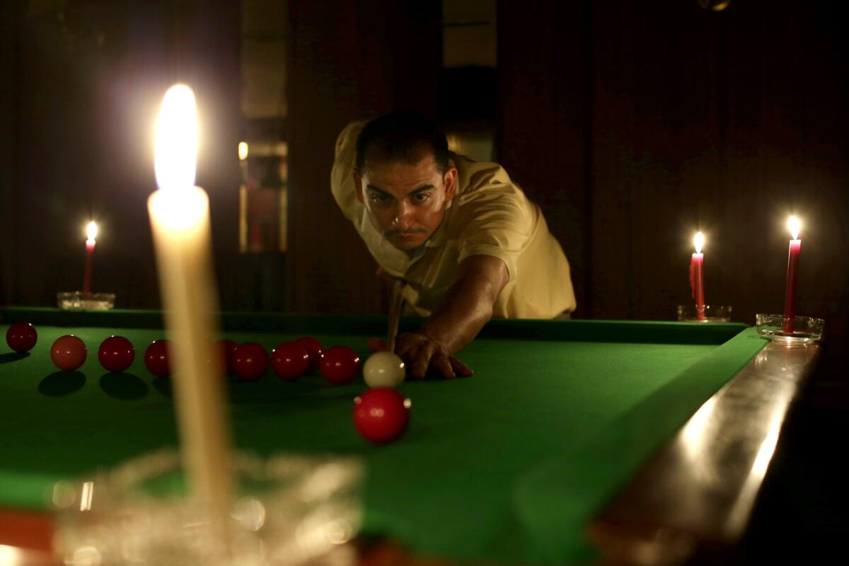 An Egyptian man plays snooker by candlelight Saturday at a club in Giza, Egypt.