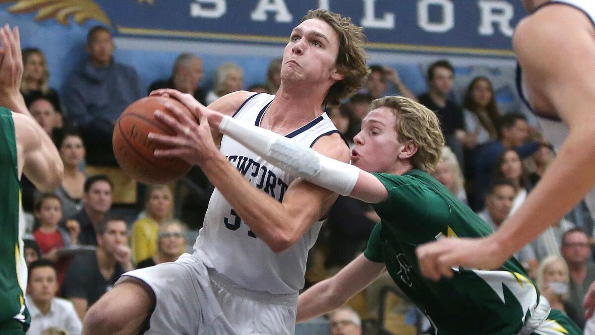 Newport Harbor's Dayne Chalmers drives the basket for a layup as Edison's Justin Strauss tries to stop him in a Surf League boys' basketball game on Friday.