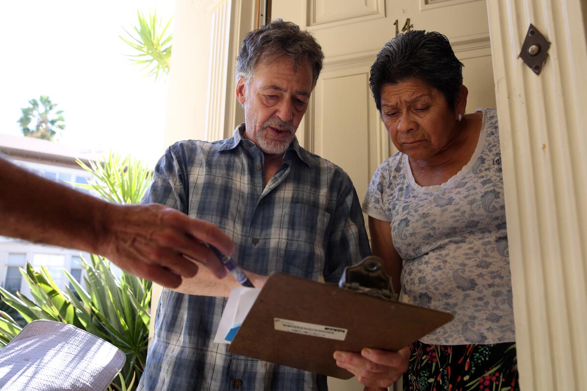 Jon Hofferman talks to fellow tenant Felicita Fuentes, right, with tenant Darrin Wilstead holding a pen at left, about their concerns with a proposed agreement with the owner of their apartment complex in Hollywood.