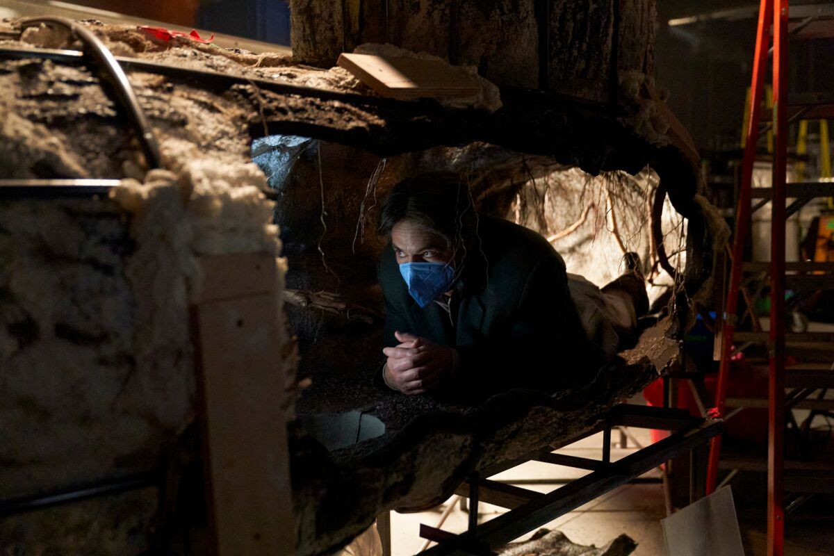 A man squeezes into a tunnel set, which required cutouts for cameras and actors.