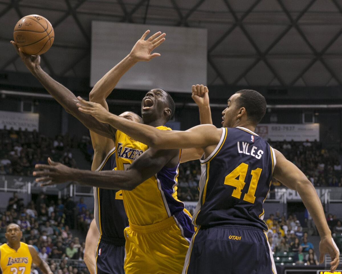 Lakers forward Brandon Bass goes up for a layup between Jazz forward Trey Lyles and center Rudy Gobert during the first half of Tuesday's preseason game.