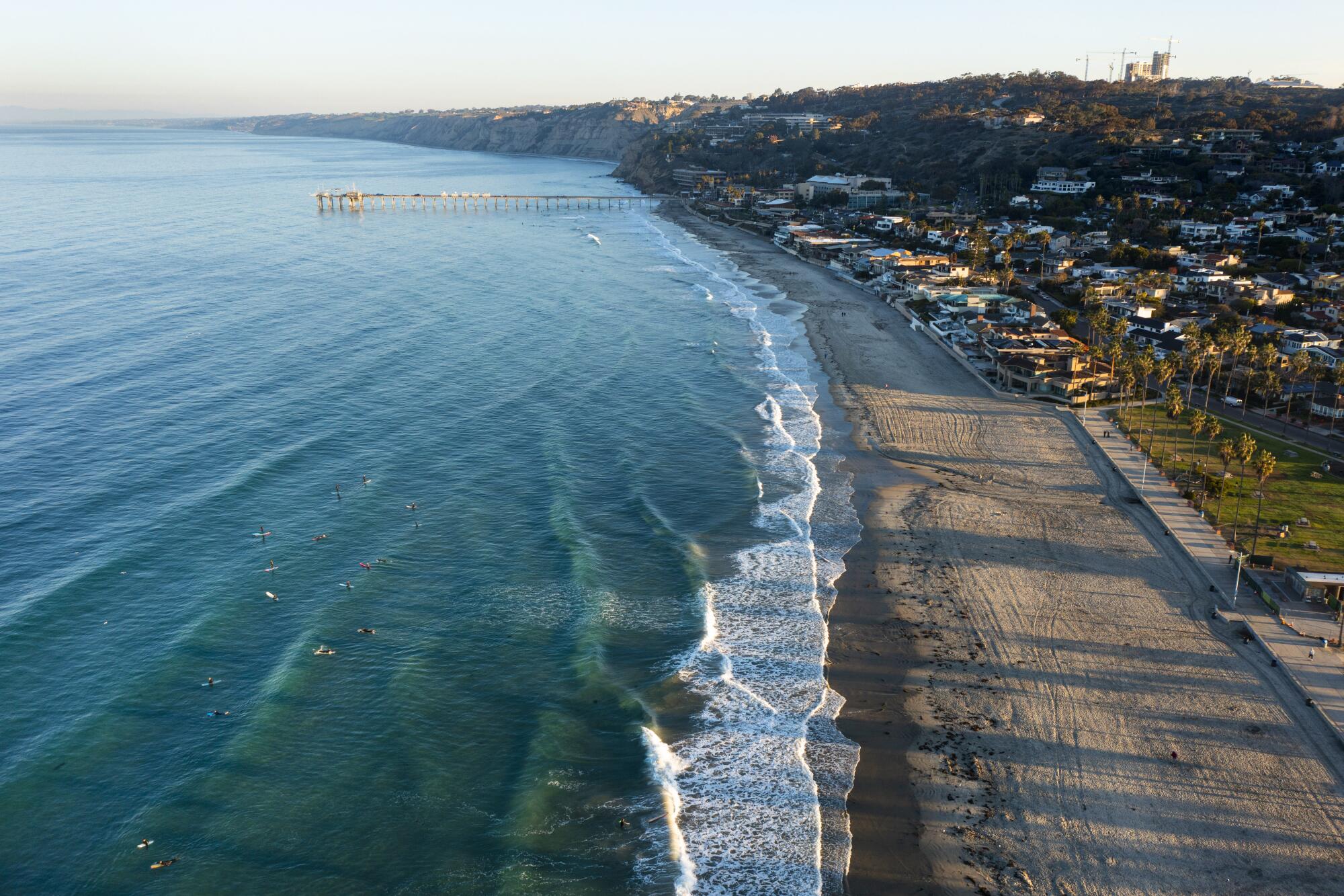 An aerial view of La Jolla Shores Beach and the waves breaking, with the Scripps Research Pier in the background.