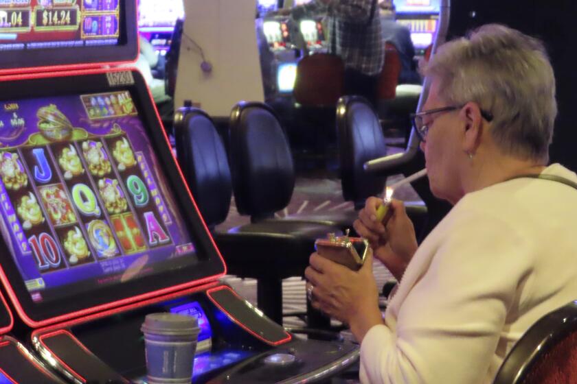 A gambler lights a cigarette at a slot machine in Harrah's casino in Atlantic City N.J. on Sept. 29, 2023. A national anti-smoking group and a Michigan health system are enlisting shareholders of major gambling companies including Boyd Gaming, Bally's, and Caesars Entertainment to push the companies to study the financial effects of eliminating smoking in their casinos. (AP Photo/Wayne Parry)