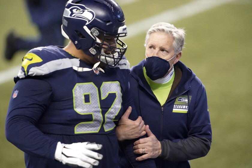 Seattle Seahawks head coach Pete Carroll, right, walks off the field with defensive tackle Bryan Mone after the team lost to the Los Angeles Rams during the second half of an NFL wild-card playoff football game, Saturday, Jan. 9, 2021, in Seattle. (AP Photo/Ted S. Warren)
