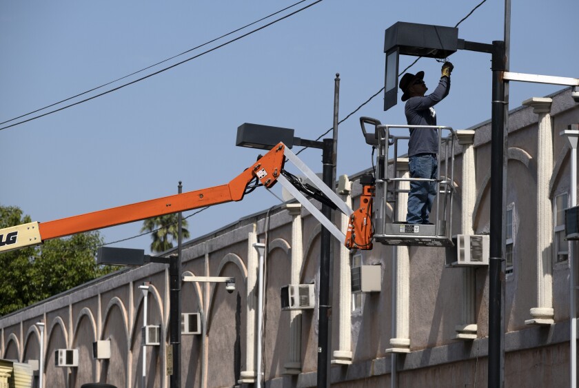 A worker fixes a street lamp in the Van Nuys section of Los Angeles on Thursday, June 17, 2021. California's power grid operator called for voluntary energy conservation Thursday as much of the state sweltered under a heat wave that has baked the U.S. West. (AP Photo/Richard Vogel)