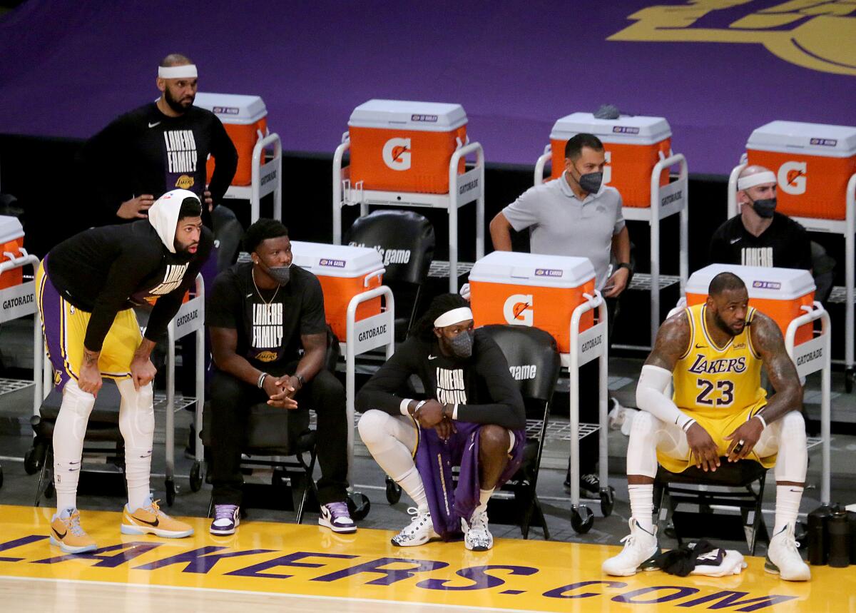 Lakers stars Anthony Davis, far left, and LeBron James (23) watch from the bench with teammates.