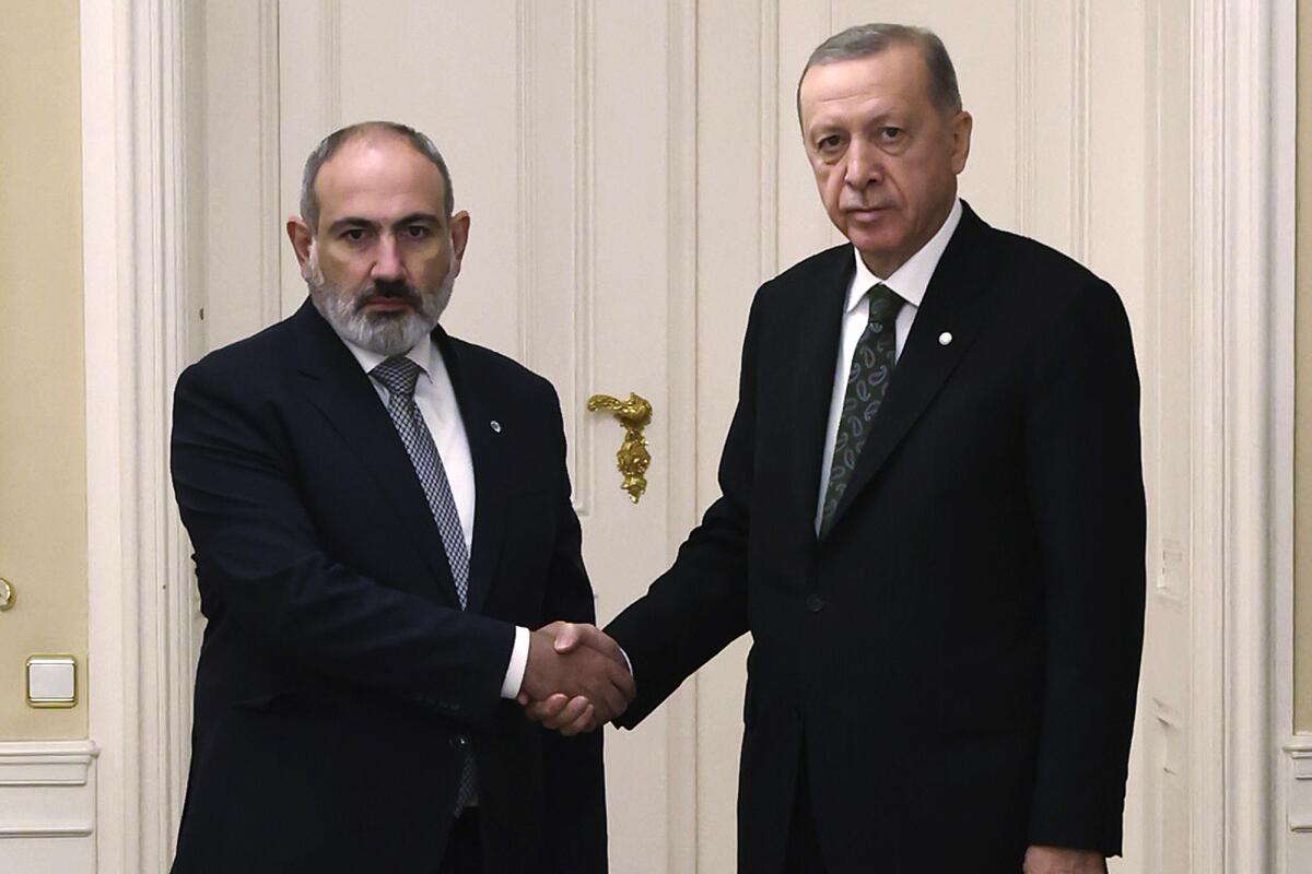 Turkey's President Recep Tayyip Erdogan, right, and Armenia's Prime Minister Nikol Pashinyan shake hands.