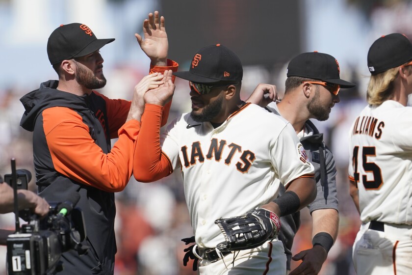 San Francisco Giants pitcher Alex Wood, left, celebrates with left fielder Heliot Ramos as the Giants beat the Miami Marlins at a baseball game in San Francisco, Sunday, April 10, 2022.  (AP Photo/Jeff Chiu)