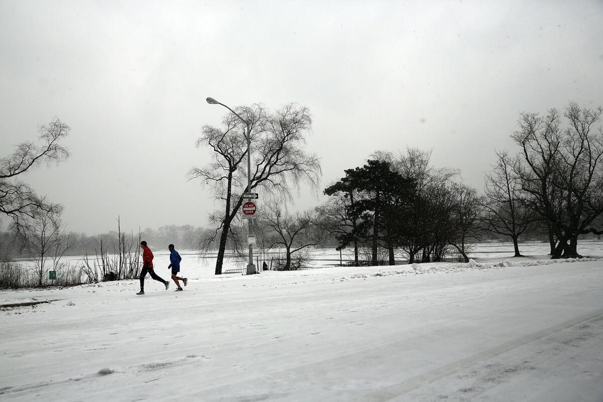 People run through Prospect Park as snow fell Saturday in the Brooklyn borough of New York.