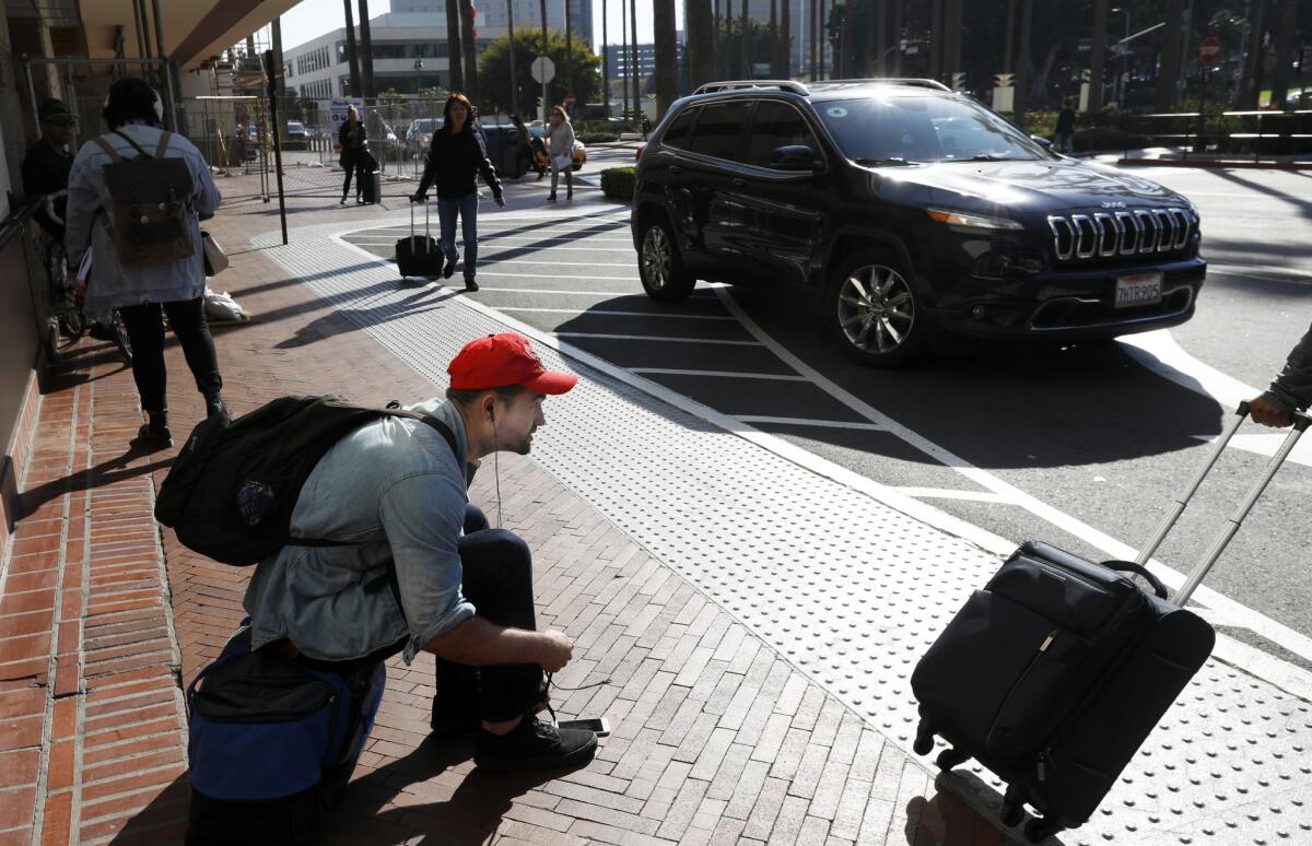William Miller ties his shoes as he waits for an Uber at Union Station in Los Angeles.