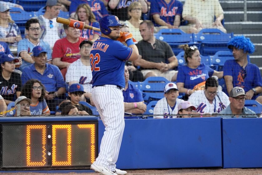 The pitch clock runs as New York Mets' Daniel Vogelbach (32) warms up on deck during the fifth inning of a spring training baseball game against the St. Louis Cardinals, Saturday, March 25, 2023, in Port St. Lucie, Fla. (AP Photo/Lynne Sladky)