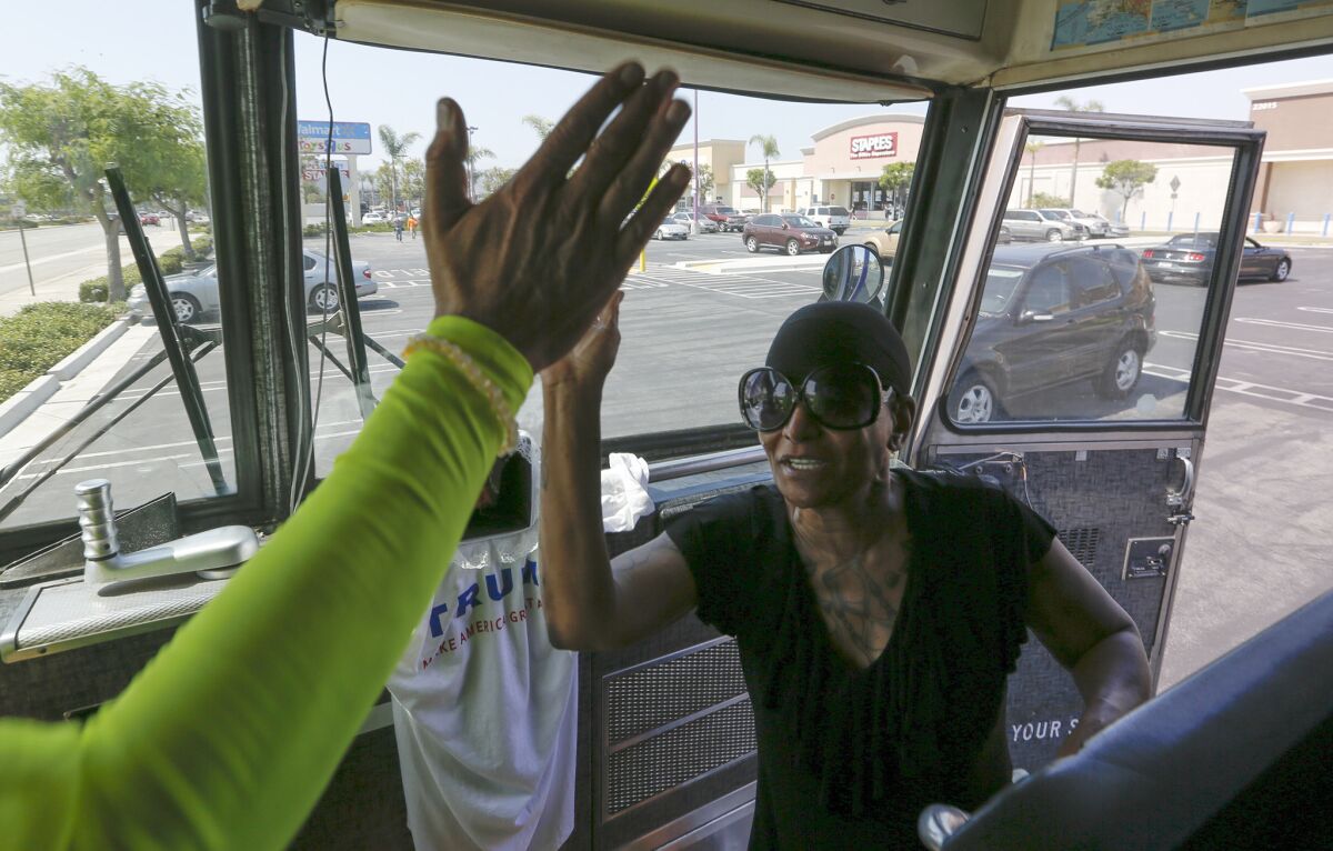 Artist David Gleeson high-fives a woman who came by his Trump bus, parked in a Wal-Mart parking lot in Torrance to volunteer her support, until she found out that the bus was an anti-Trump statement.