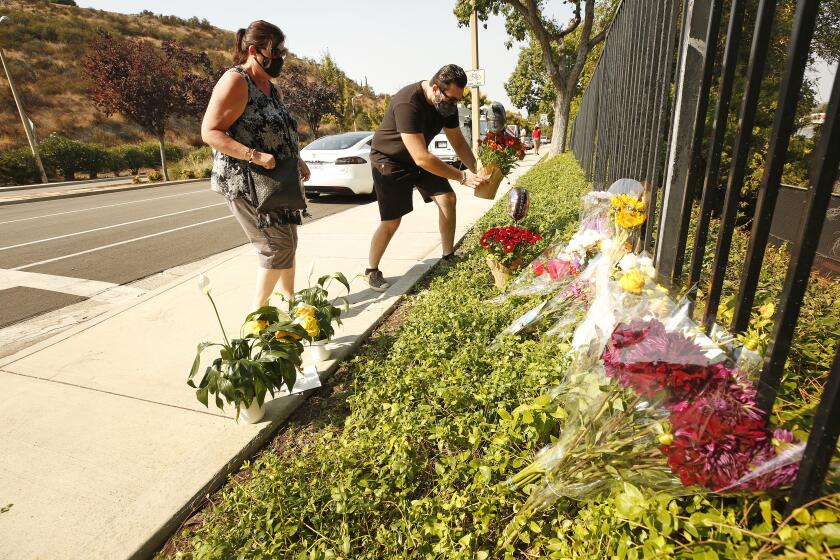 WESTLAKE VILLAGE, CA - SEPTEMBER 30: Lorraine Maralian and her son Anthony Maralian of Westlake Village place flowers and pray at a growing memorial for two brothers who were fatally injured while crossing Triunfo Canyon Road at Saddle Mountain Drive in their Westlake Village neighborhood with their family at 7:10 pm Tuesday evening. Rebecca Grossman, 57, a co-founder of the Grossman Burn Foundation was arrested on two counts of vehicular manslaughter in the death of the two juvenile pedestrians that were in the crosswalk and is being held on $2 million bail. Westlake Village on Wednesday, Sept. 30, 2020 in Westlake Village, CA. (Al Seib / Los Angeles Times