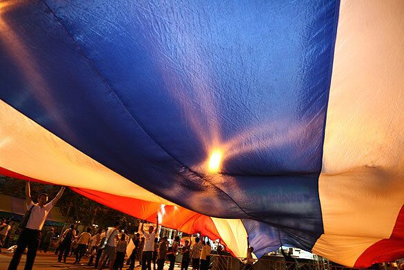 Thai pro-government supporters wave a giant Thai flag at the Royal Plaza in Bangkok, Thailand. Four grenade explosions in the area killed three and injured 75 people, sparking night-long street battles between pro- and anti-government protesters.