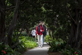 Encinitas, California - December 29: Ethan Cohen, 26, left, and Cheyenne Blaisdell, 26, walk a path in the newly reopened Meditation Gardens at Self-Realization Fellowship on Wednesday, Dec. 29, 2021 in Encinitas, California. The garden had been closed for nearly two years because of the coronavirus. (Ana Ramirez / The San Diego Union-Tribune)