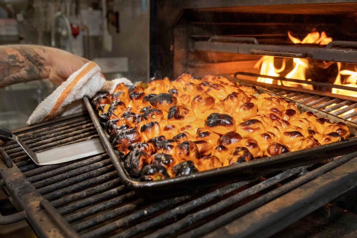 A tray of roasted chiles pulled out of an oven.