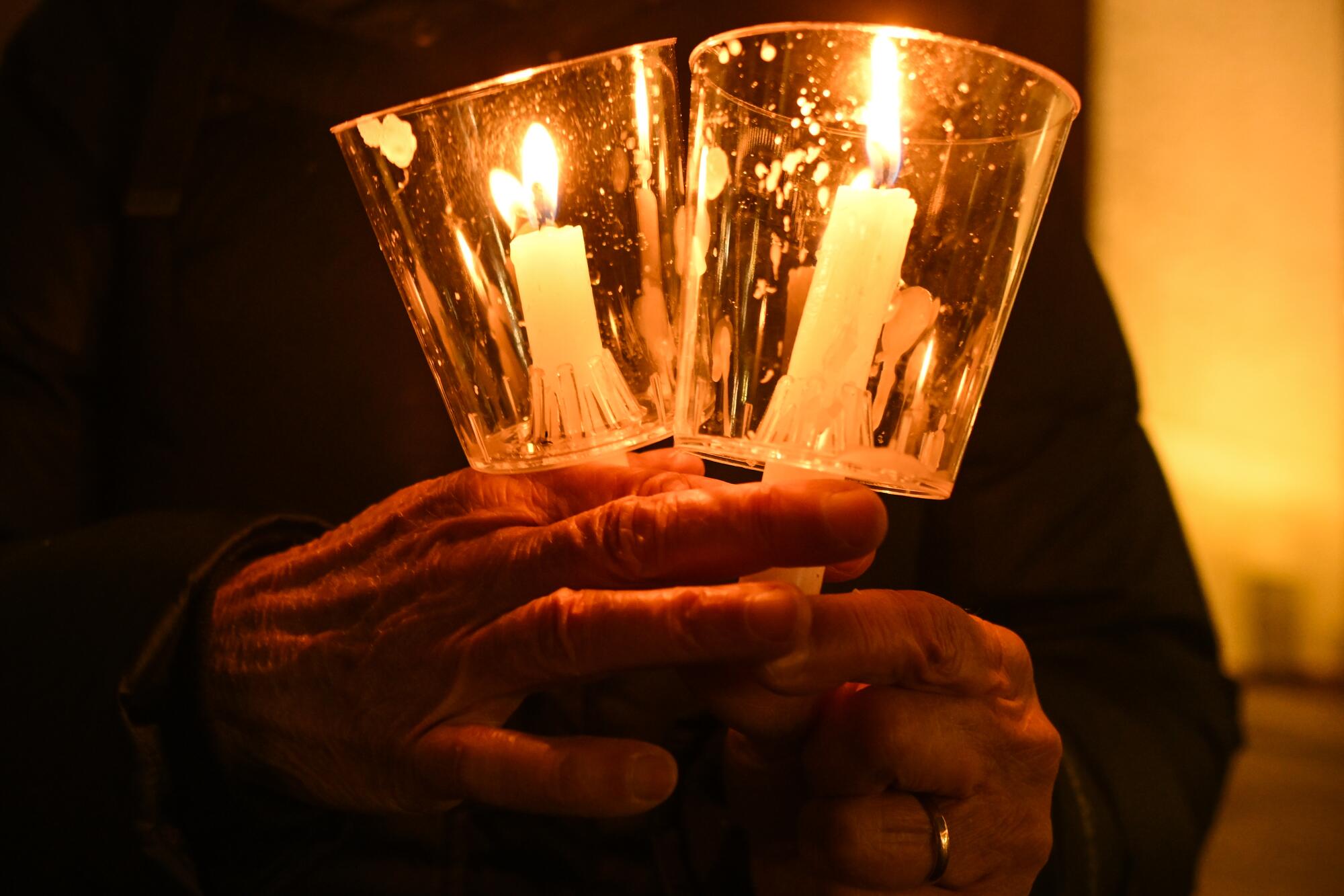Hands hold two lighted candles