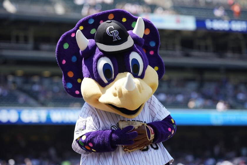 FILE - Colorado Rockies mascot Dinger in shown in the first inning of a baseball game in Denver, in this Sunday, July 18, 2021, file photo. The Colorado Rockies said a fan suspected of repeatedly yelling a racial slur at Florida outfielder Lewis Brinson was actually hollering at “Dinger,” the club's purple, polka-dotted dinosaur mascot.The team said Monday, Aug. 9, 2021, that fans who were seated nearby contacted the club in defense of the fan after it put out a statement saying it was disgusted by epithets hurled at Brinson when he was up in the ninth inning of Colorado's 13-8 victory Sunday. The club then contacted the fan, who explained it was just a big misunderstanding and that he was only trying to get the attention of Dinger, who was two sections over. (AP Photo/David Zalubowski, File)