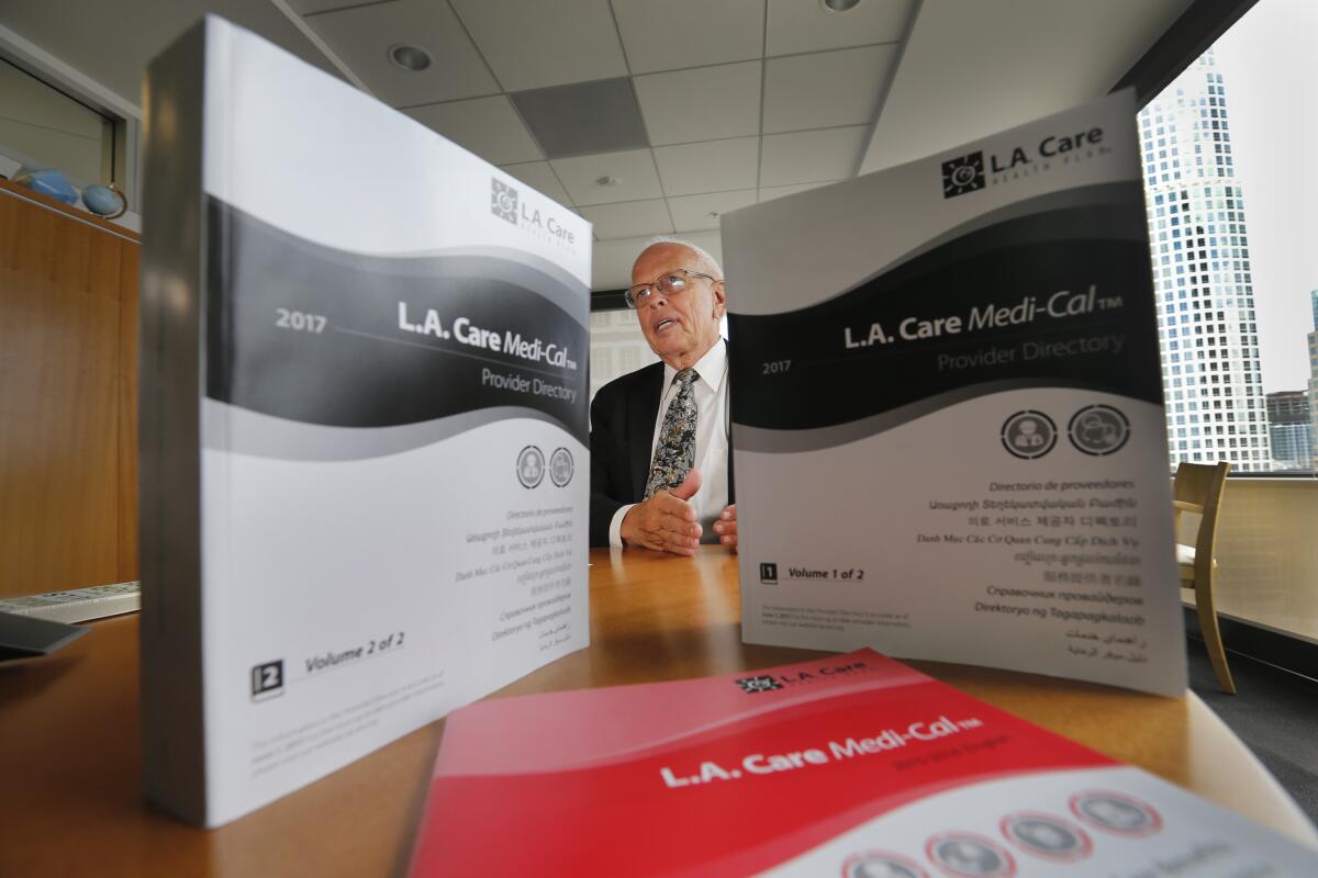 A man in a suit sits at a table behind two volumes of L.A. Care Medi-Cal provider directories.