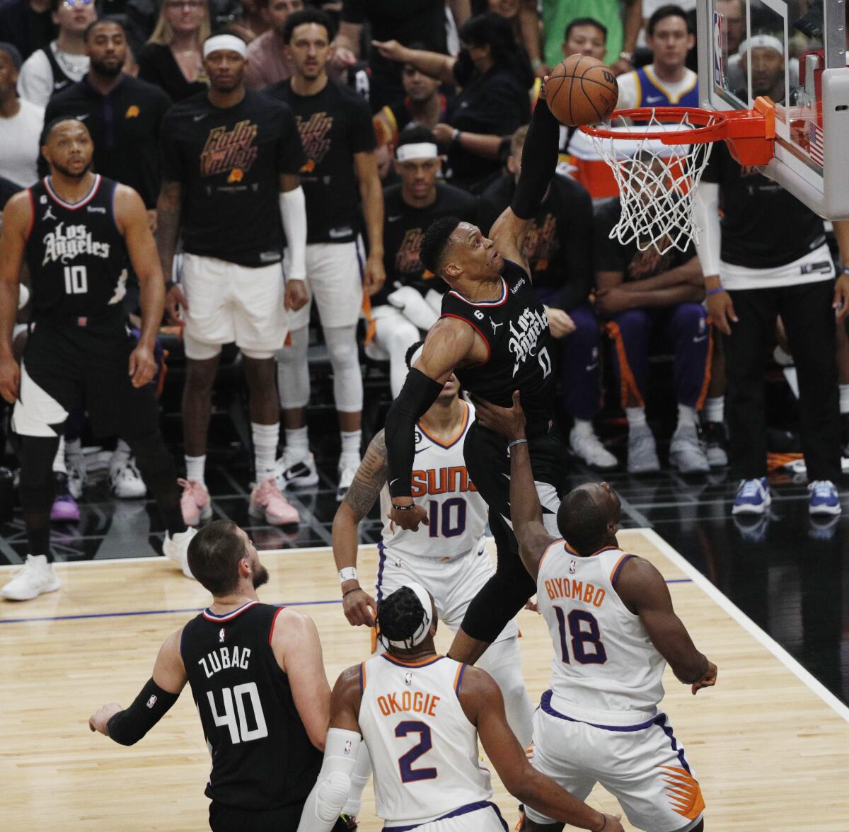 Russell Westbrook dunks as a trio of Phoenix Suns watch him in the first half Saturday.