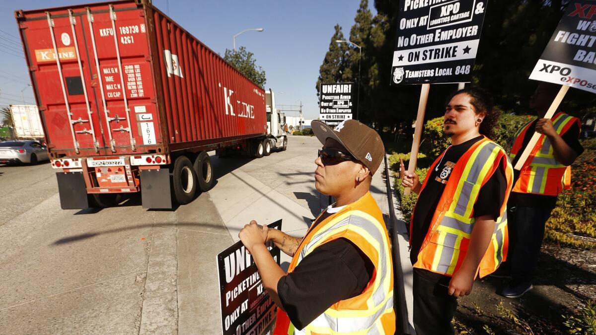 Sandra Vega, left, and Cesar Castro, both shop stewards, join workers on strike at the Intermodal Container Transfer Facility in Wilmington on Monday morning.