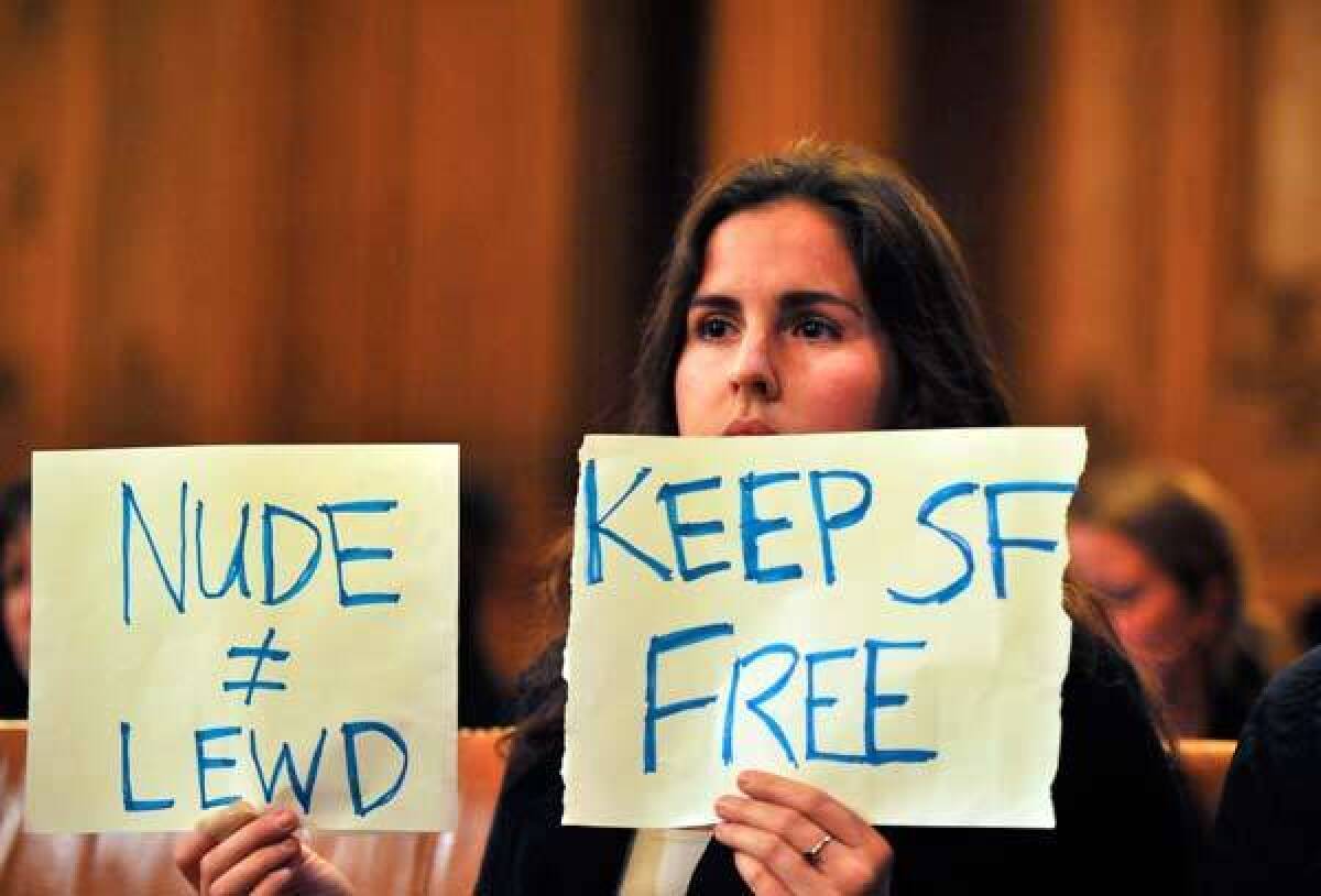 Tailor Whitfield holds up a sign during a Board of Supervisors meeting in San Francisco's City Hall.
