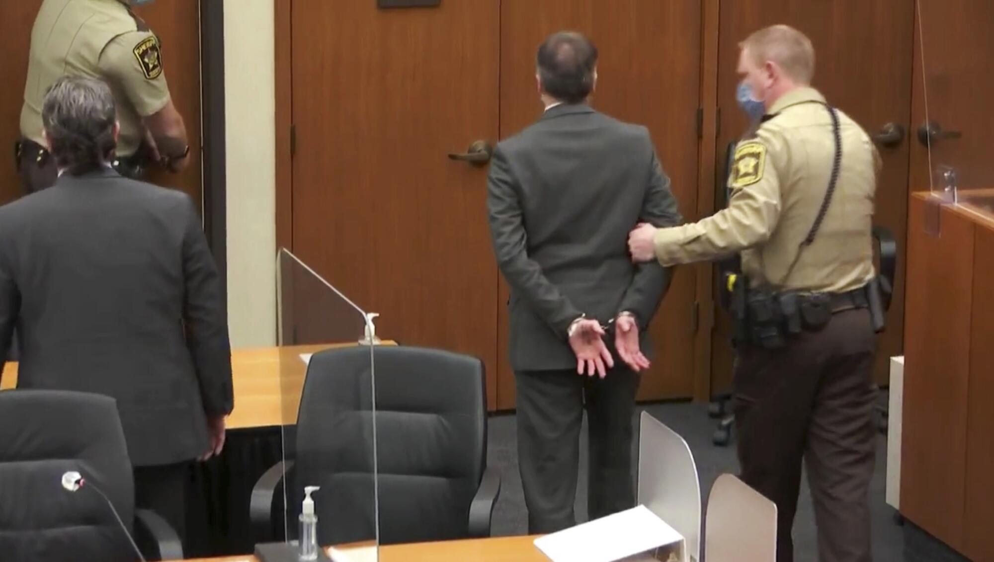 Former Minneapolis police Officer Derek Chauvin, center, is taken into custody as his attorney, Eric Nelson, left, looks on.