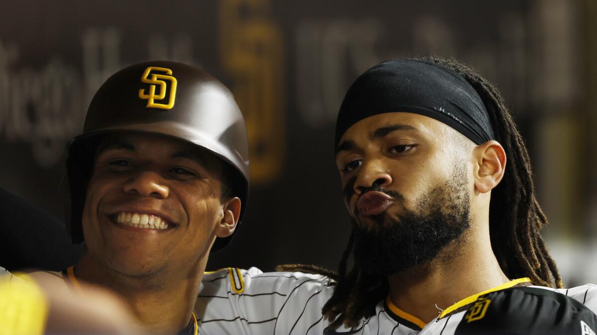 San Diego Padres' Nelson Cruz, center, is congratulated by Rougned Odor  (24) as Fernando Tatis Jr. (23) looks on after Cruz hit a solo home run  during the eighth inning of the