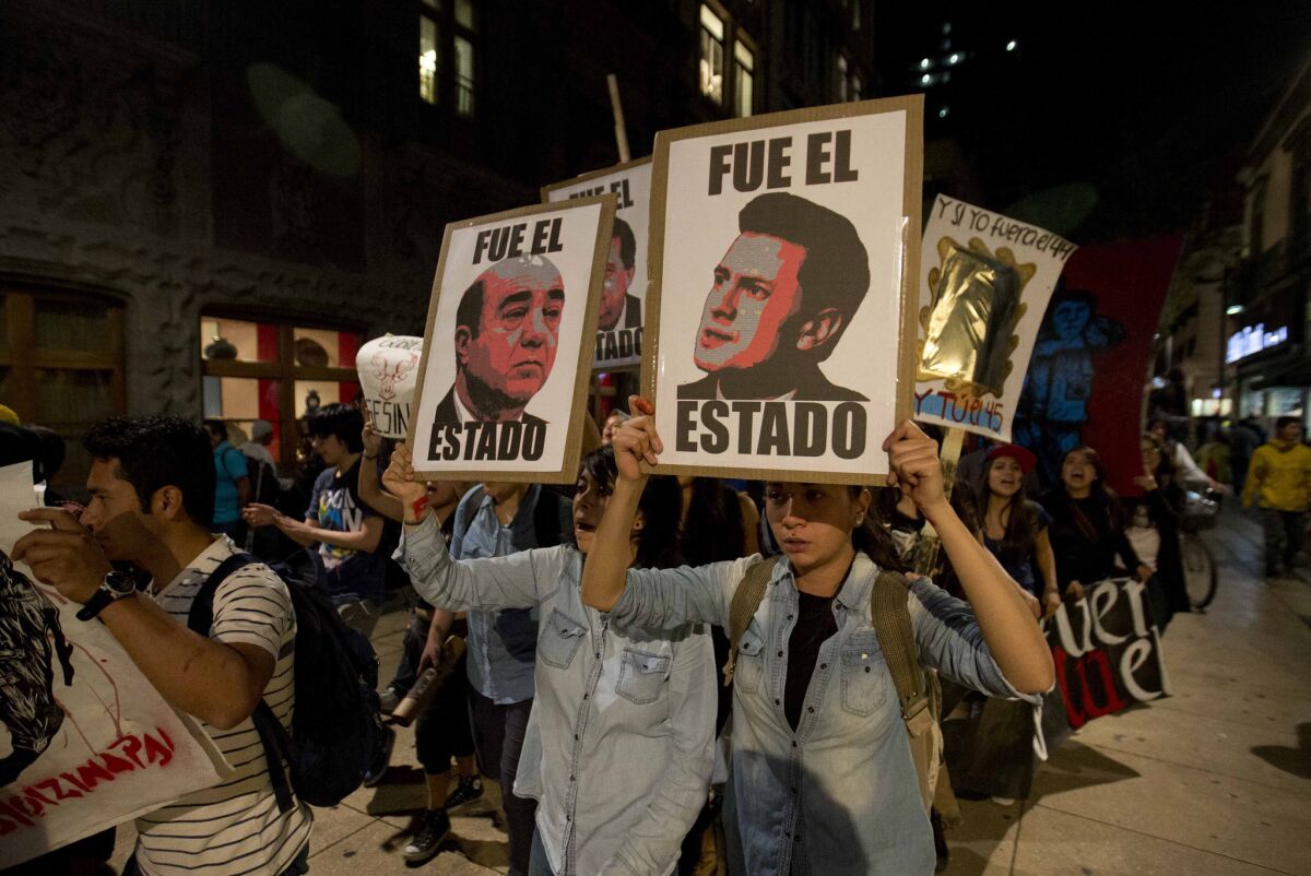 In Mexico City, demonstrators march with signs saying "It was the state" and showing images of Mexican President Enrique Peña Nieto, right, and Atty. Gen. Jesus Murillo Karam in a protest over the disappearance of 43 college students.