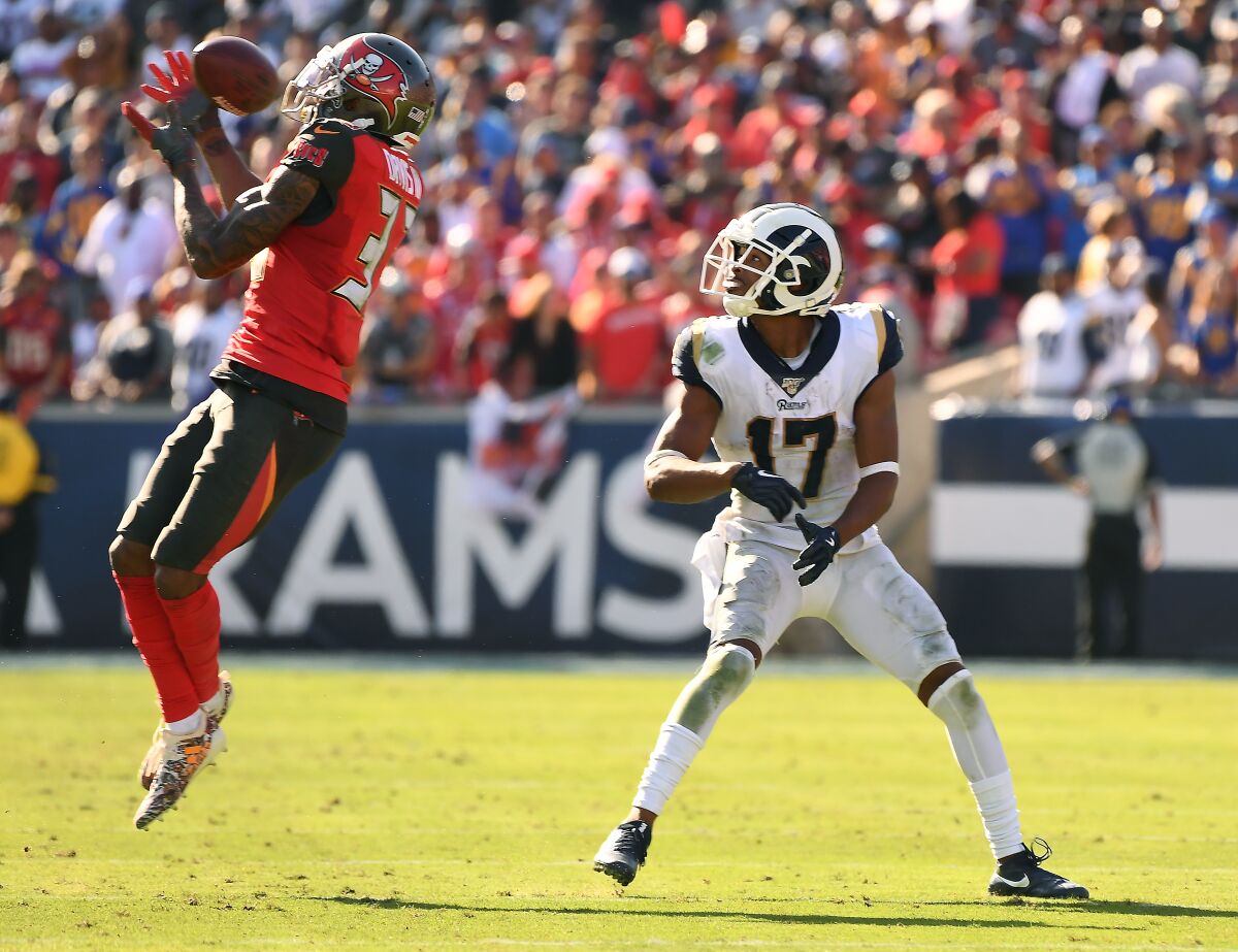 Tampa Bay Buccaneers cornerback Carlton Davis, left, intercepts a pass intended for Rams wide receiver Robert Woods during the fourth quarter on Sunday.