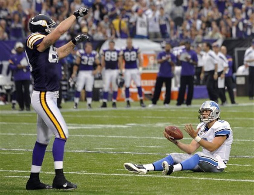 Detroit Lions quarterback Matthew Stafford, right, sits on the turf in front of Minnesota Vikings defensive end Jared Allen, left, after getting sacked during the second half an NFL football game Sunday, Sept. 25, 2011, in Minneapolis. (AP Photo/Jim Mone)