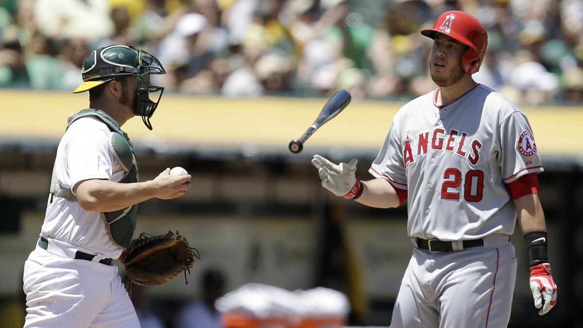 Angels first baseman C.J. Cron, right, reacts to striking out in front of Oakland Athletics catcher Sonny Gray during the second inning of the Angels' 6-3 loss Sunday.