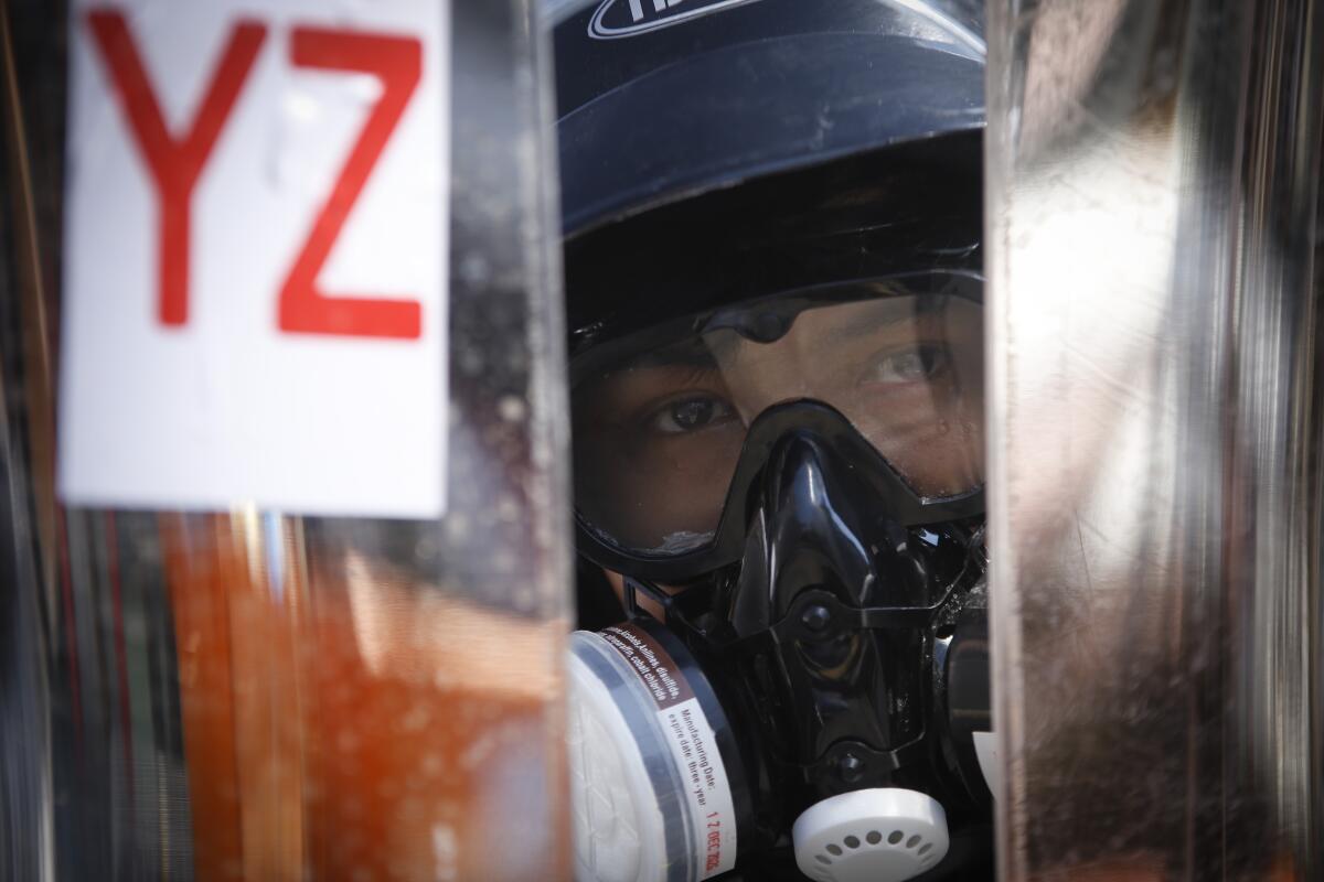 A protester wearing helmet and gas mask takes positions behind a makeshift barricade in Yangon, Myanmar.