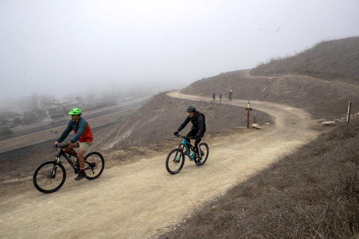 Mountain bikers pedal up a fog-shrouded trail at the Pismo Preserve.