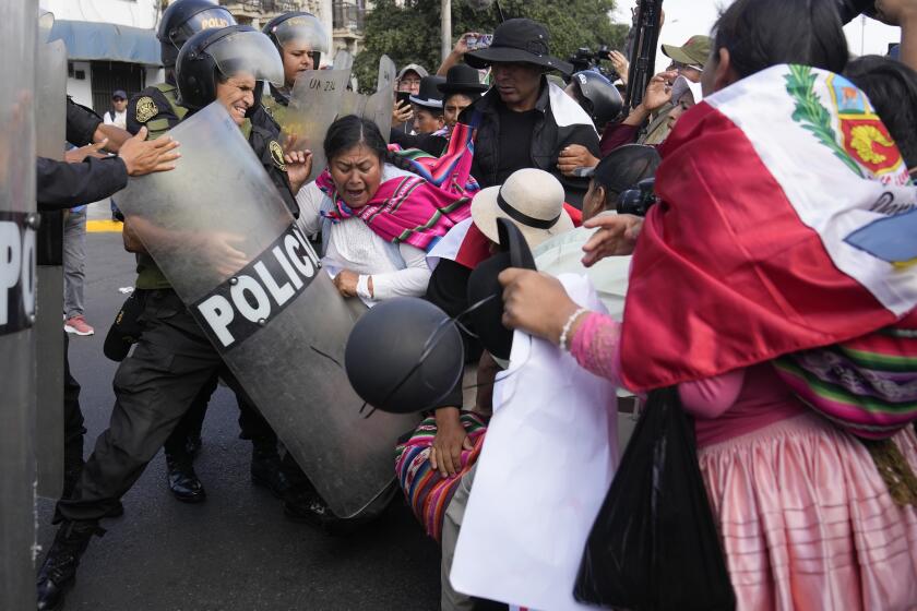 Manifestantes contra el gobierno empujan a un agente antimotines en una protesta por el Día Internacional de los Trabajadores en Lima, Perú, el miércoles 1 de mayo de 2024. (AP Foto/Martín Mejía)